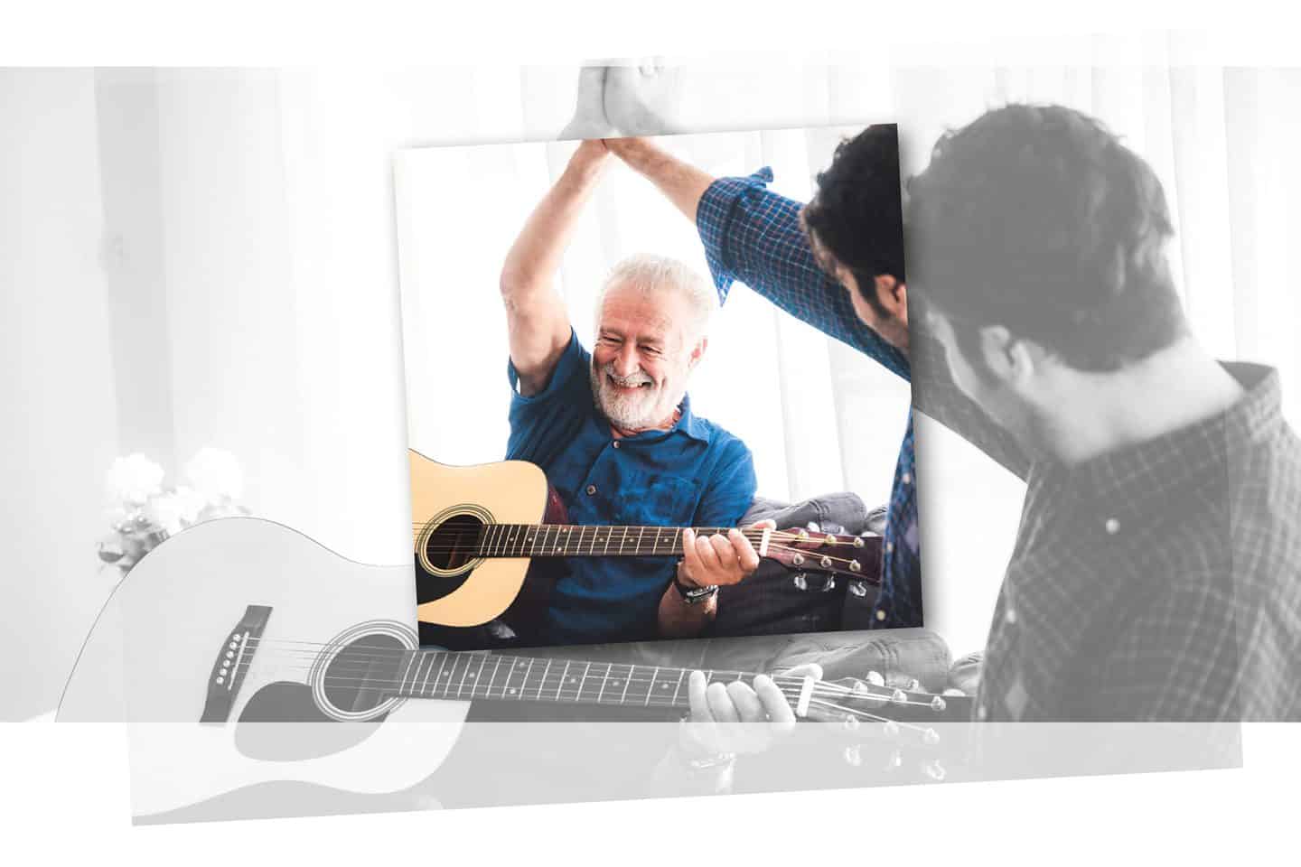 Ein Senior mit Gitarre high fived lachend einen bärtigen Pfleger.