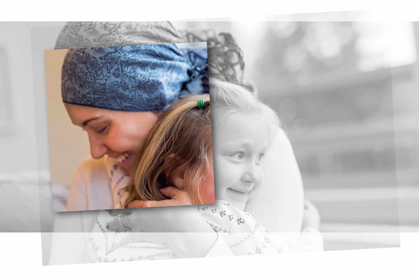 Eine Mutter mit blau gemustertem Kopftuch umarmt seelig lächelnd ihre junge Tochter.